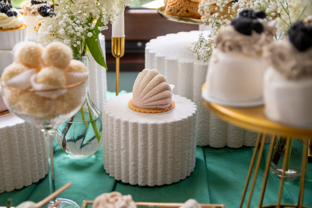 Słodki stół w odcieniach bieli i złota – elegancja na zielonym tle